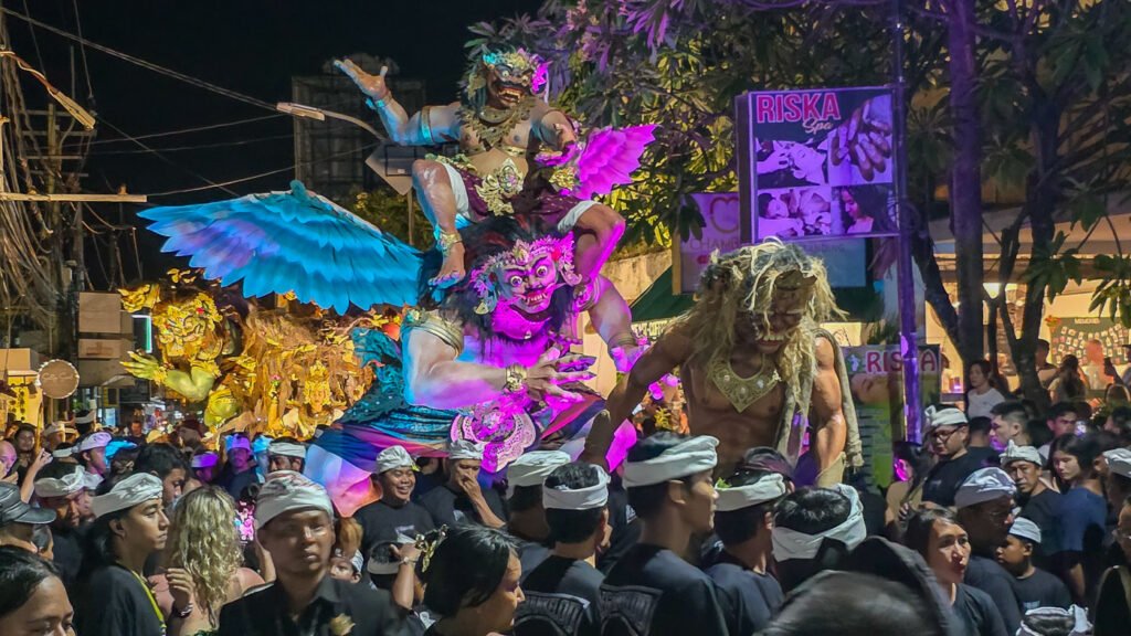 Ogoh-Ogoh parade in Bali at night with crowds carrying large demon statues through fire and smoke