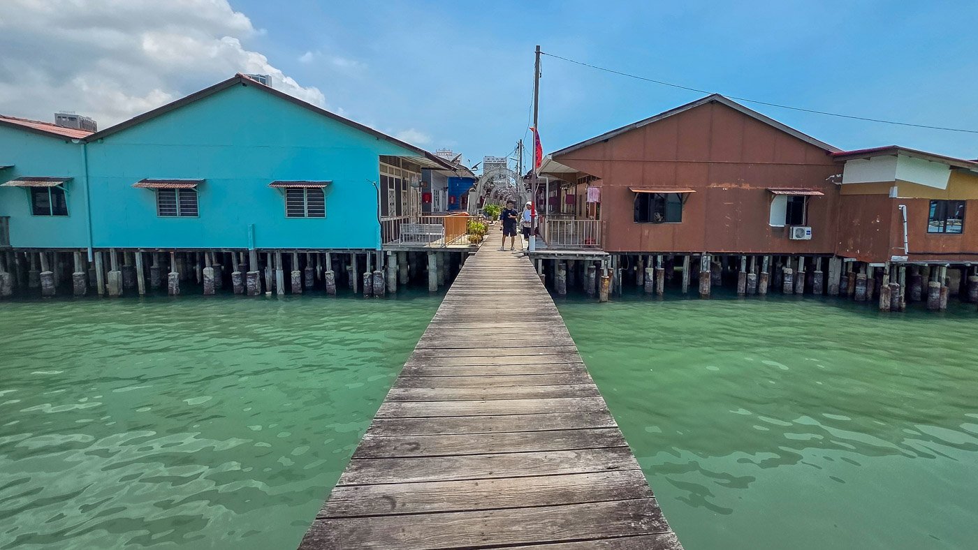 Symmetrical wooden walkway between colorful houses at Chew Jetty in Penang, symbolizing trust, direction, and coherence.